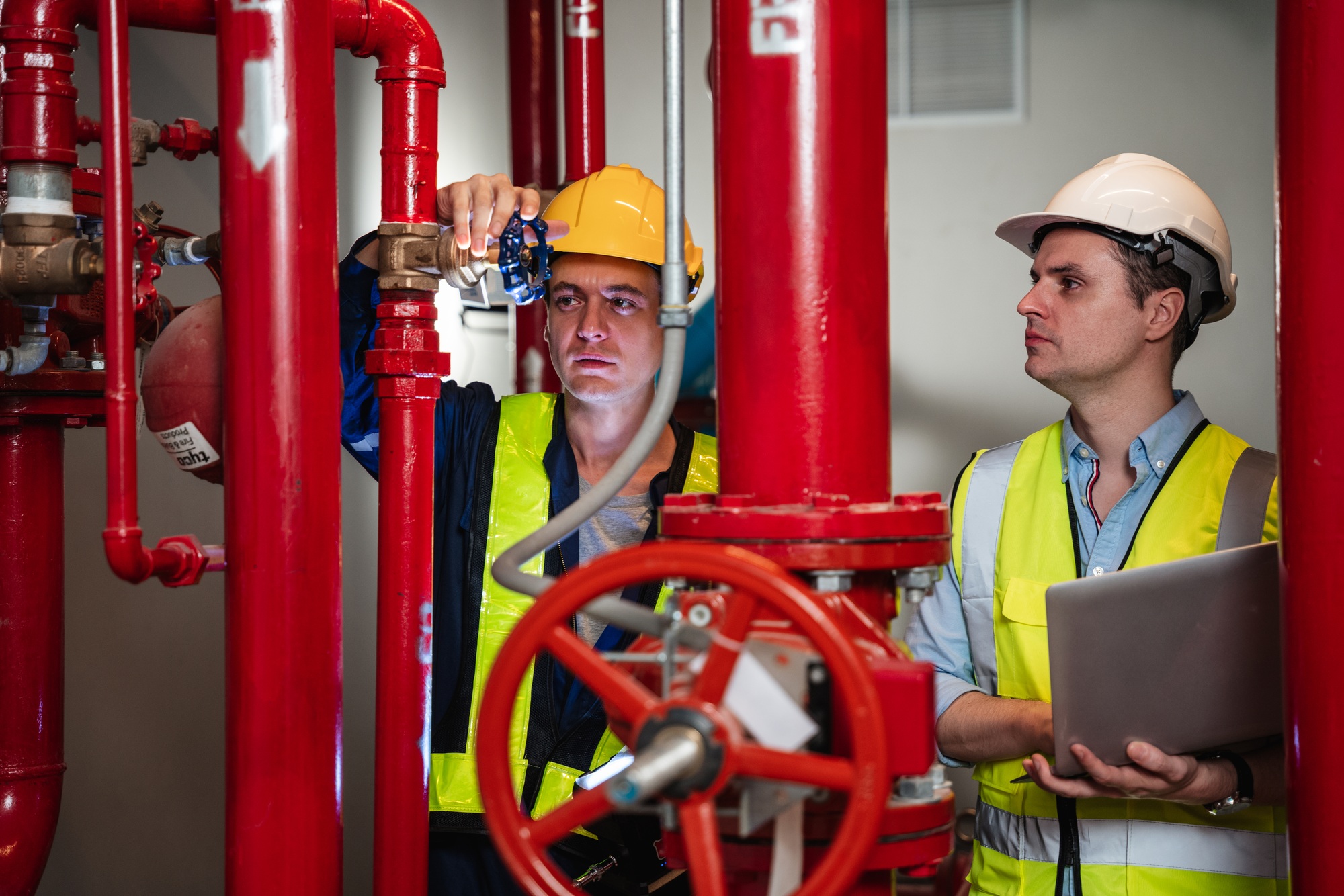 Engineers are inspecting the plumbing and water valves inside an industrial facility.